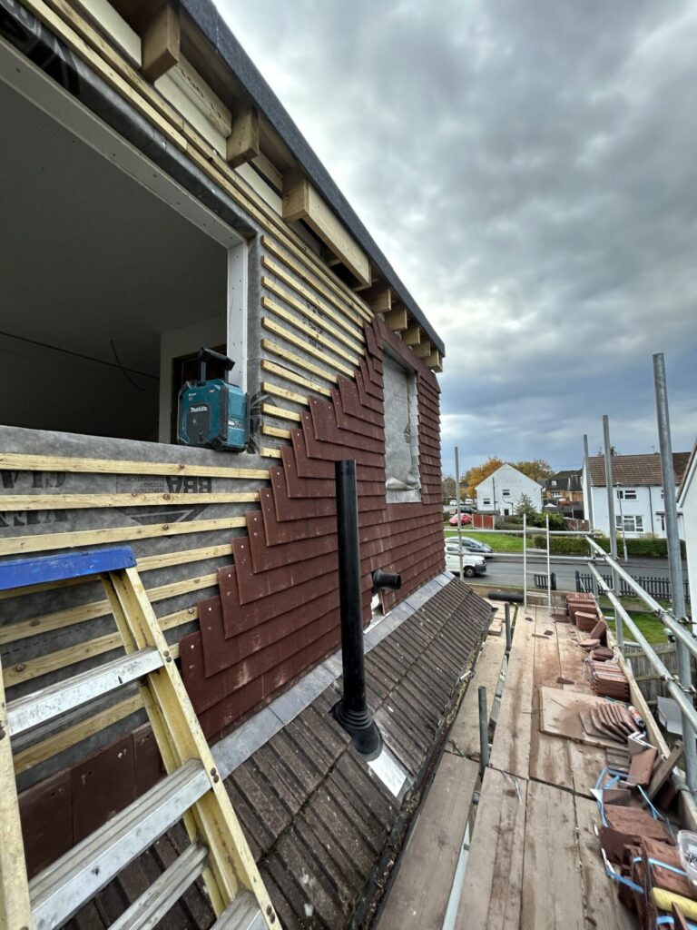 Dormer loft conversion with external timber cladding and roofing work in progress, delivering durable and high-quality structural finishes.