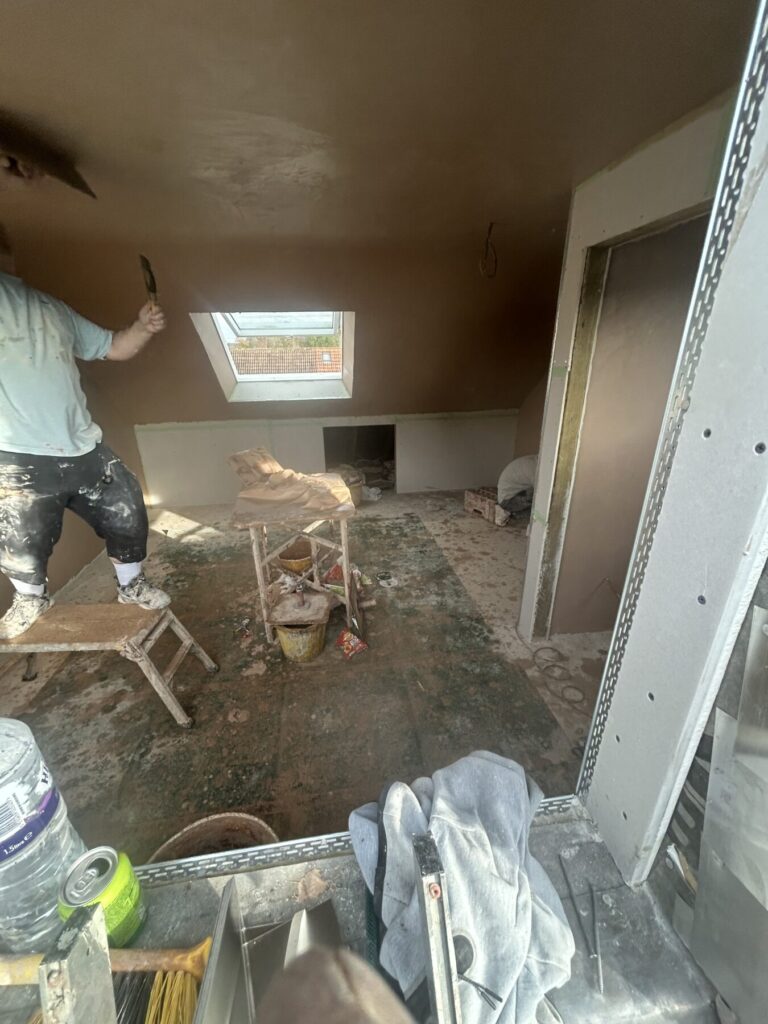 Interior loft plastering and finishing stage with skylight installation, preparing the space for final decoration and completion.