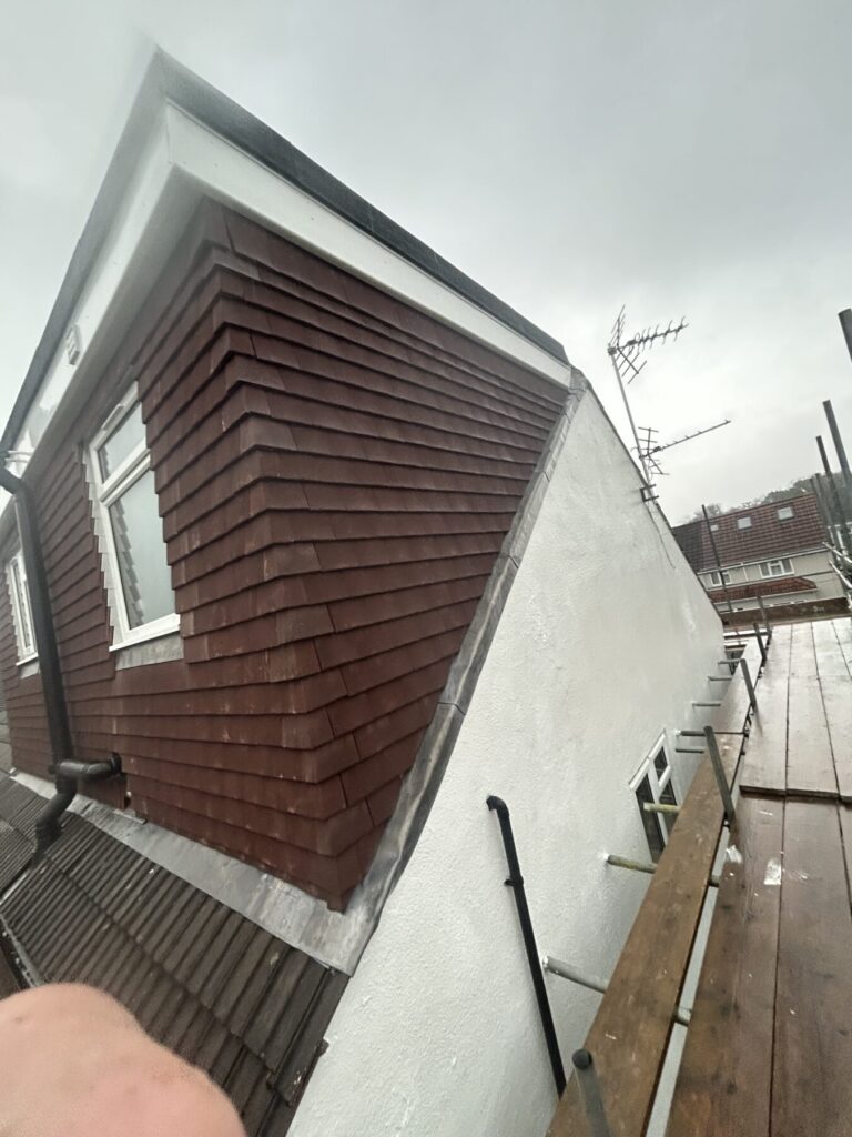 Dormer roof construction with timber cladding and scaffolding on residential property