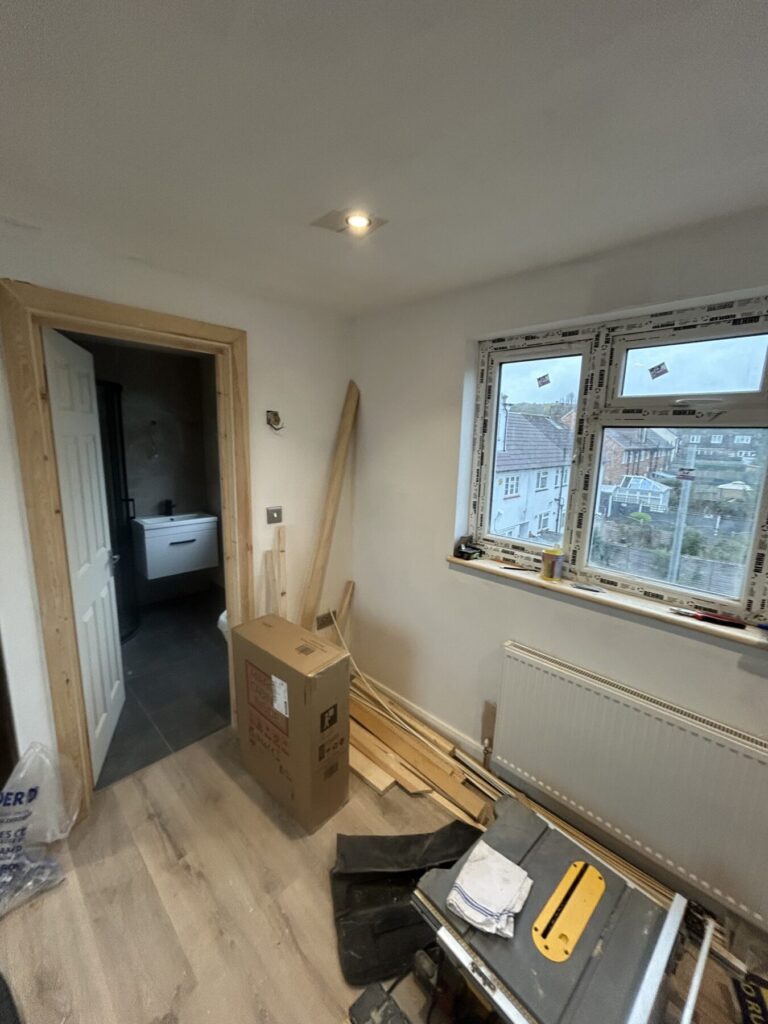 Modern bathroom with newly fitted window, wall-mounted sink unit, and wooden floor
